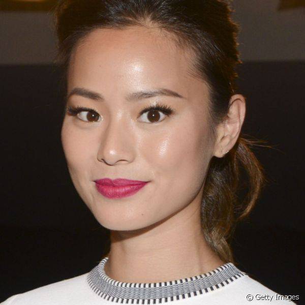 A atriz Jamie Chung adicionou cor ao seu look branco com um rosa vibrante nos lábios e sombra preta nos olhos